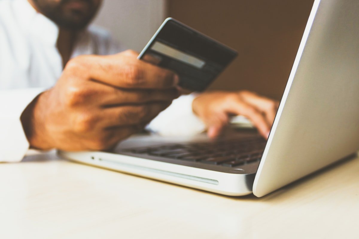 Person using a payment card and laptop while checking a suspicious PayPal invoice scam